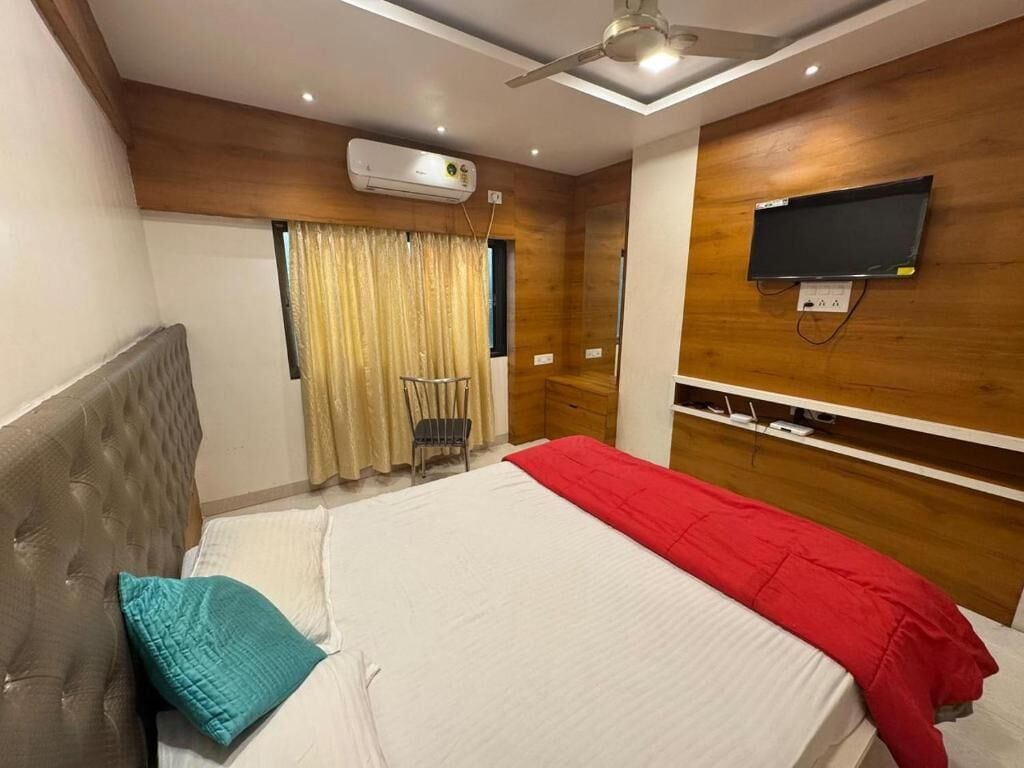Een hotelkamer met een bed, een aan de muur bevestigde televisie en een plafondventilator.