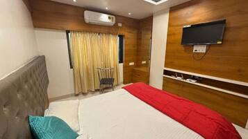 Een hotelkamer met een bed, een aan de muur bevestigde televisie en een plafondventilator.