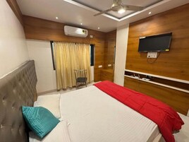 Una habitación de hotel con una cama, un televisor montado en la pared y un ventilador de techo.