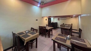 Un comedor con varias mesas y sillas, ventiladores de techo e iluminación empotrada.