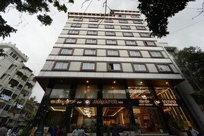 A multi-story hotel with a modern facade, large windows, and signage for 'AMMAPUR VEG' and 'VYO'. - VOVO Boutique Hotel (BENGALURU)