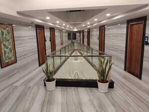A hotel lobby with a central glass table, marble walls, wooden doors, and potted plants. - VOVO Boutique Hotel (BENGALURU)