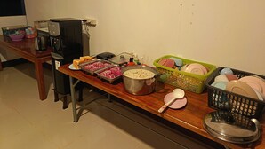 A buffet table with food items, a coffee maker, and various kitchen utensils.