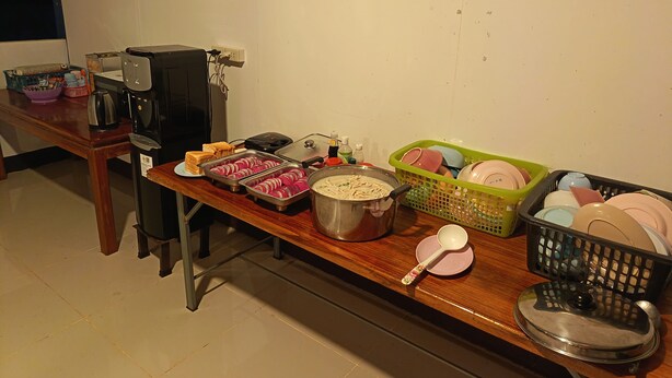 Una mesa de buffet con alimentos, una cafetera y varios utensilios de cocina.