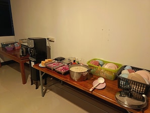 A buffet table with food items, a coffee maker, and various kitchen utensils.
