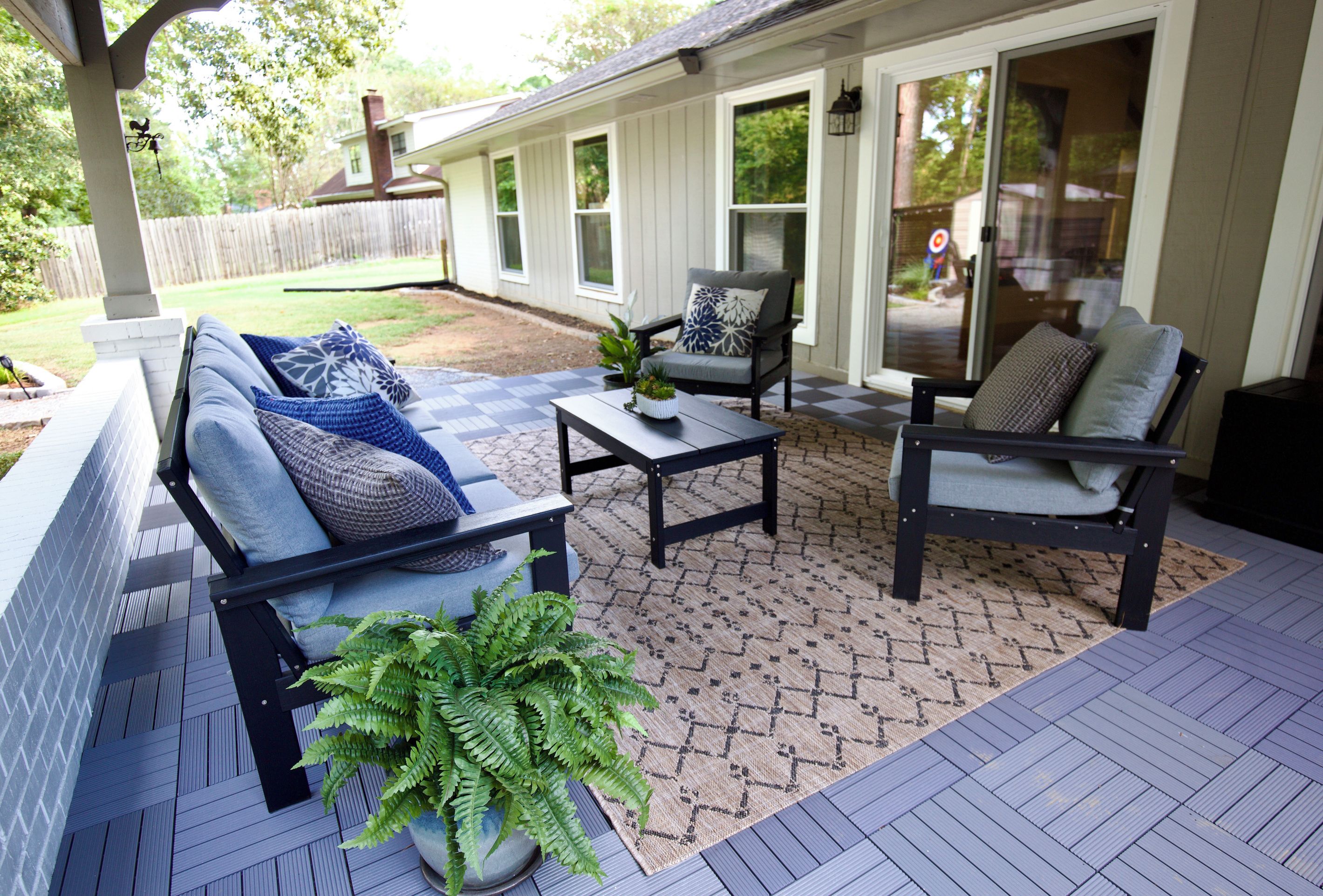 A covered patio with a seating area, a coffee table, and a potted plant.