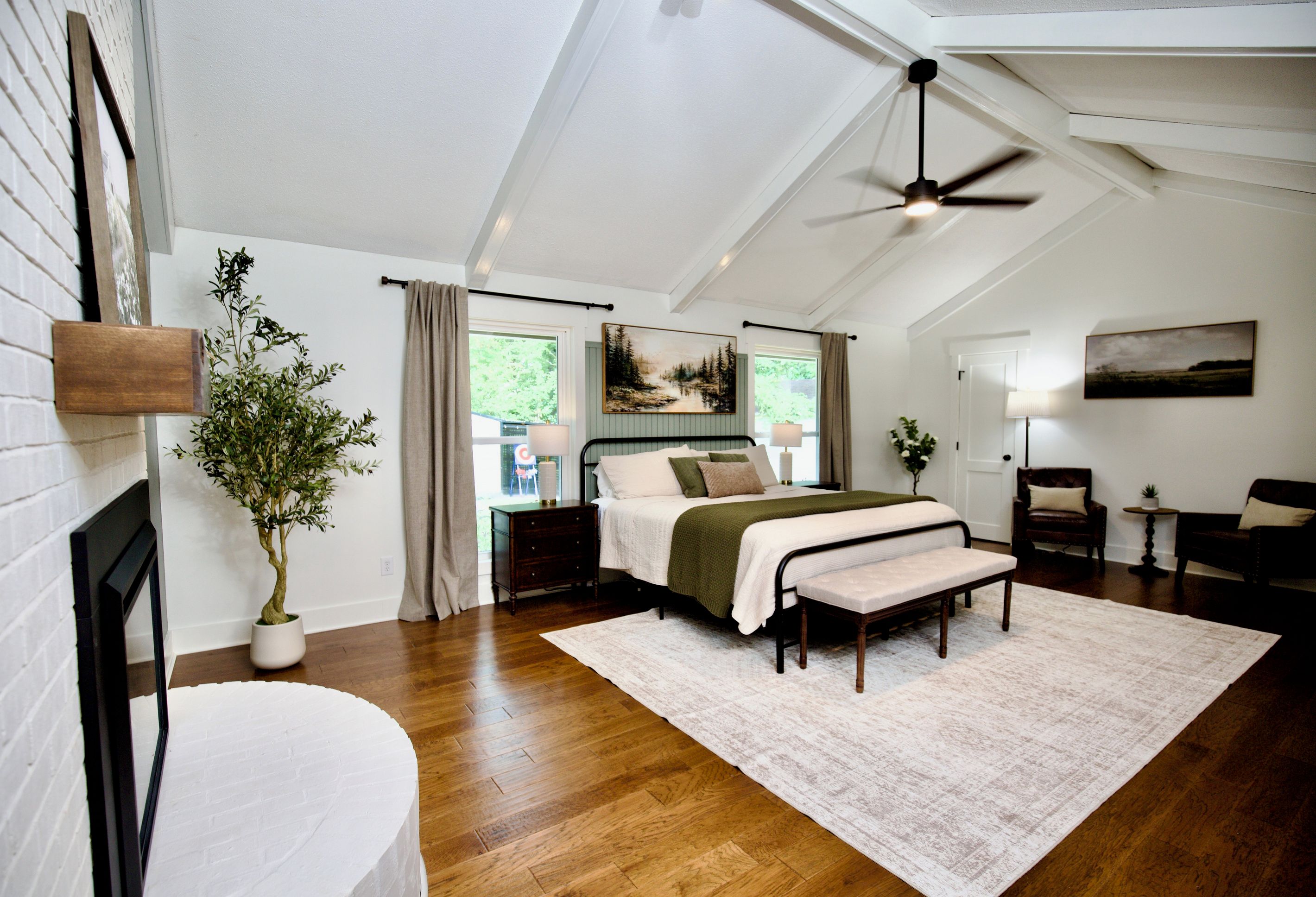 Quarto com cama, mesas de cabeceira, ventilador de teto e vista para o exterior.