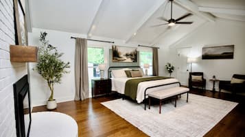 Quarto com cama, mesas de cabeceira, ventilador de teto e vista para o exterior.