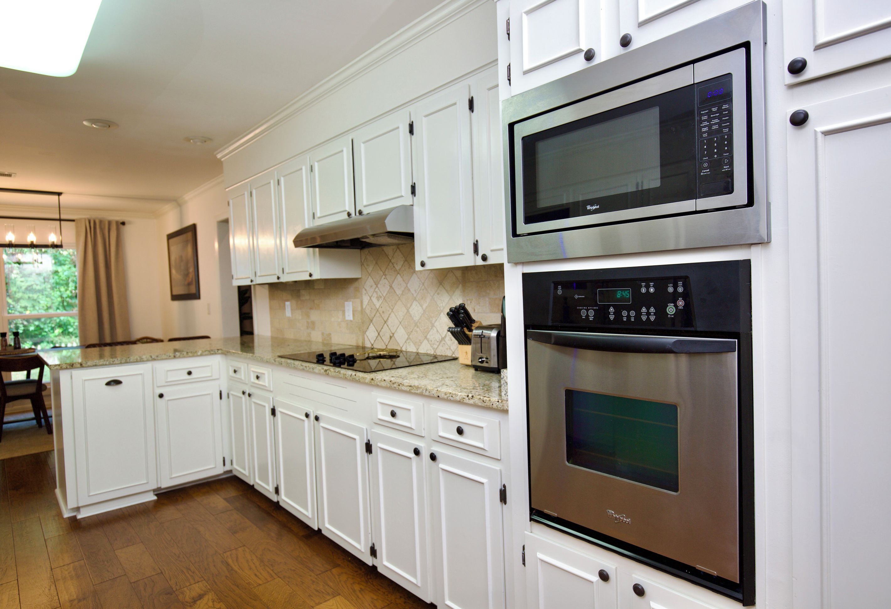 A modern kitchen with white cabinetry, stainless steel appliances, and a granite countertop.