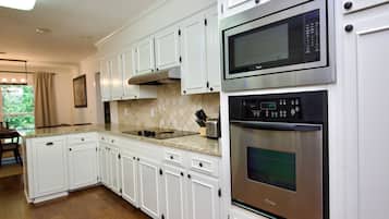 A modern kitchen with white cabinetry, stainless steel appliances, and a granite countertop.