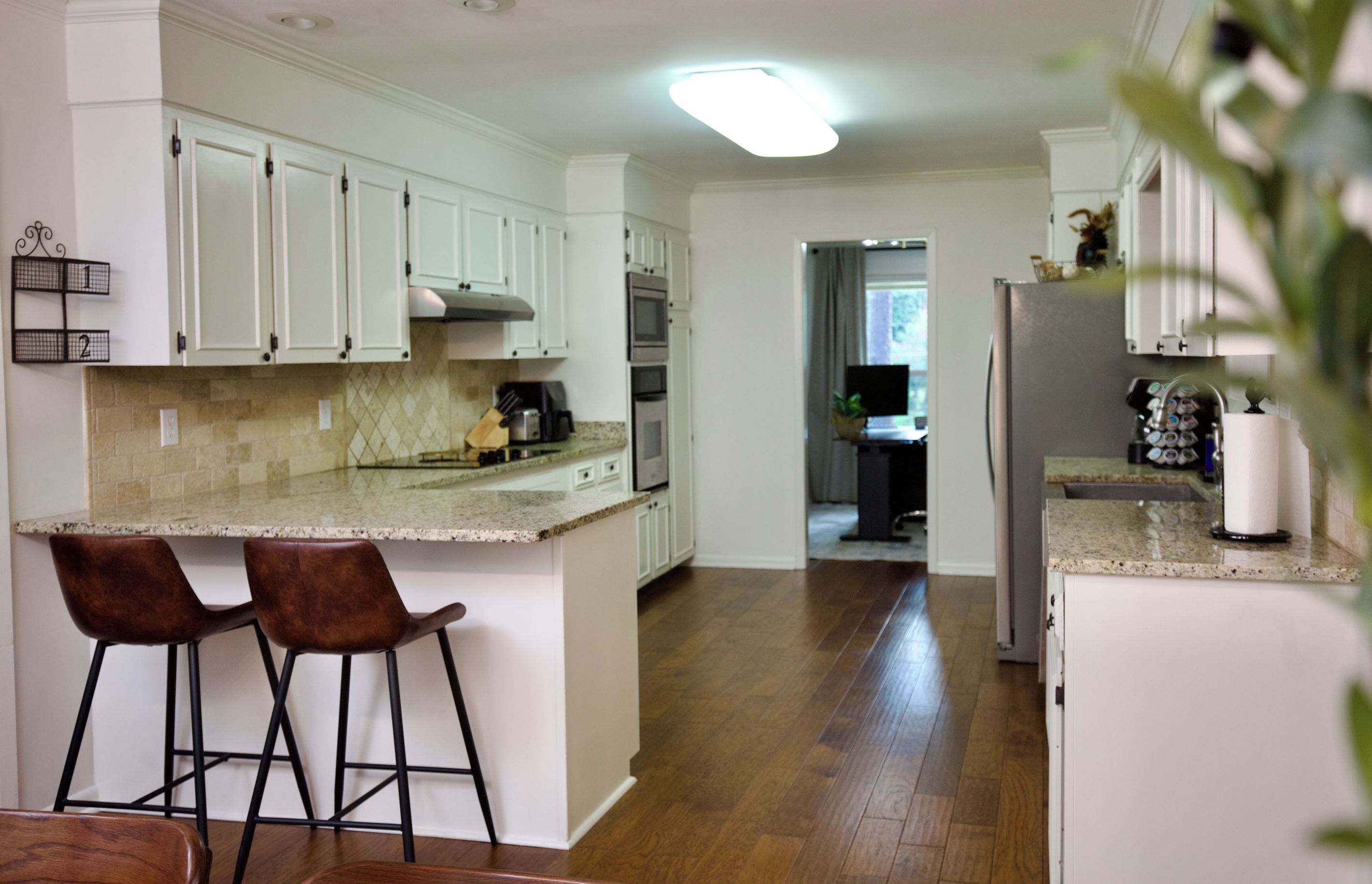 A kitchen with white cabinets, a granite countertop, and a stainless steel refrigerator.