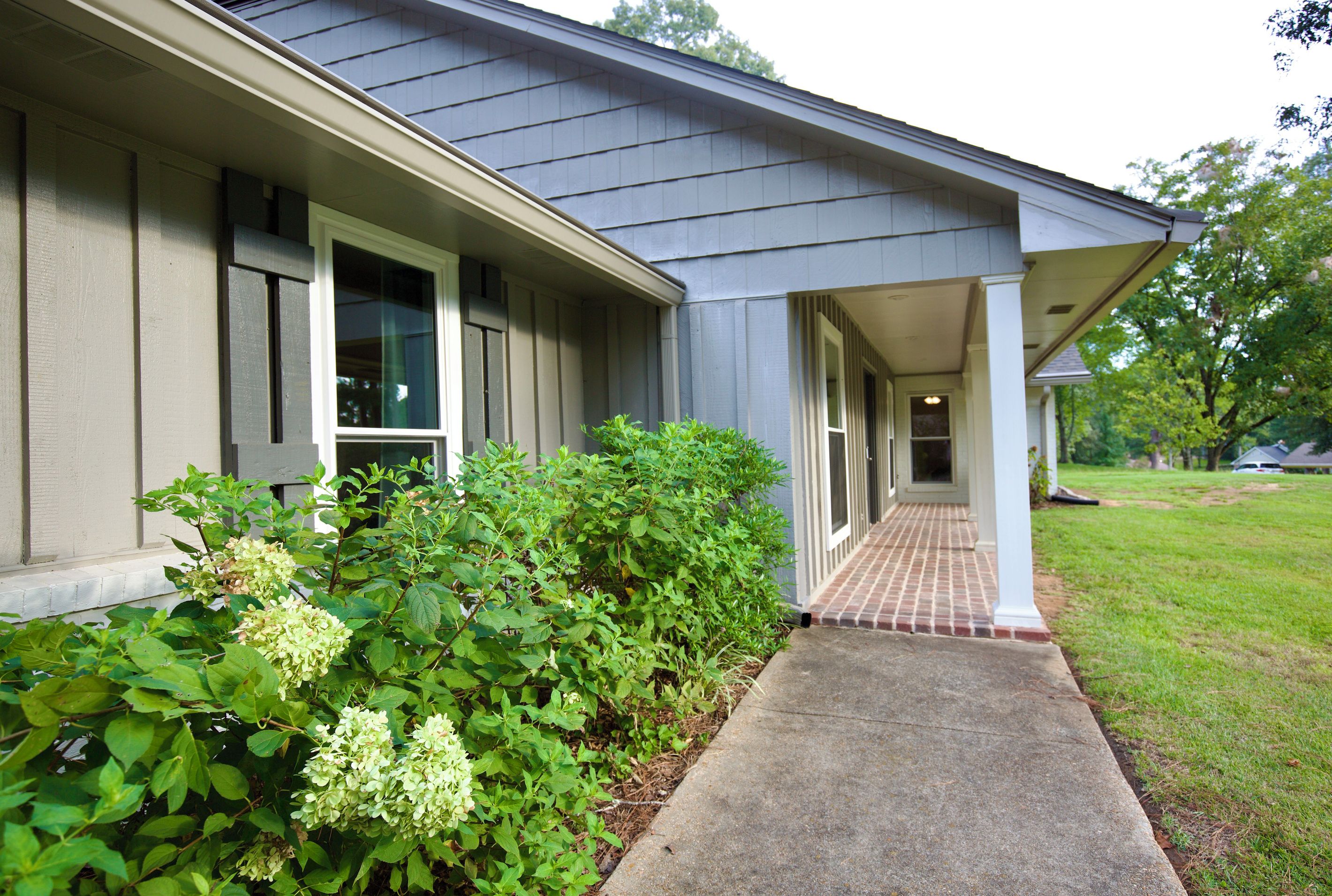 A residential house with a covered porch and a brick pathway leading to the entrance.