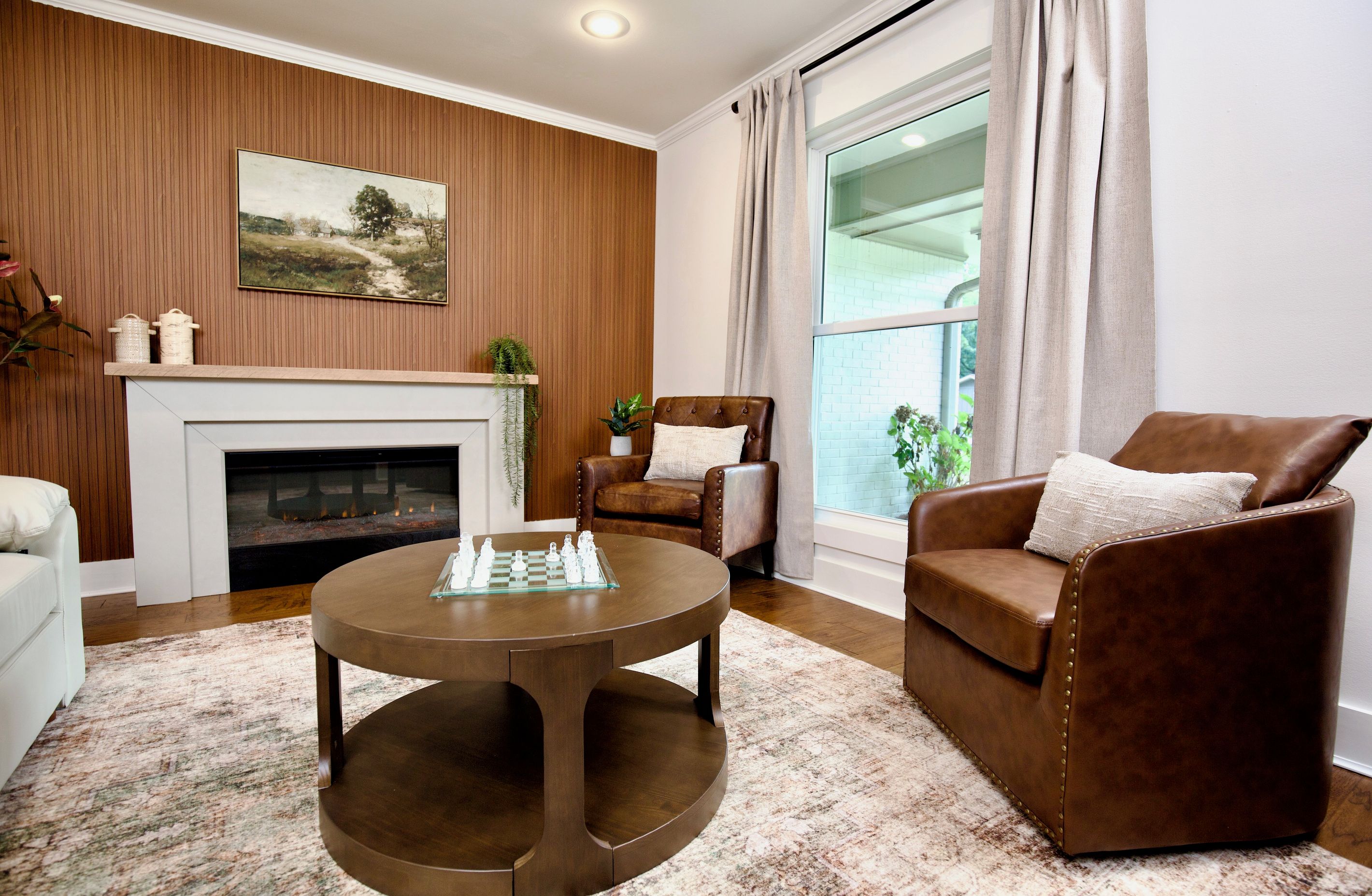 A living room with a fireplace, a chessboard, and leather armchairs.