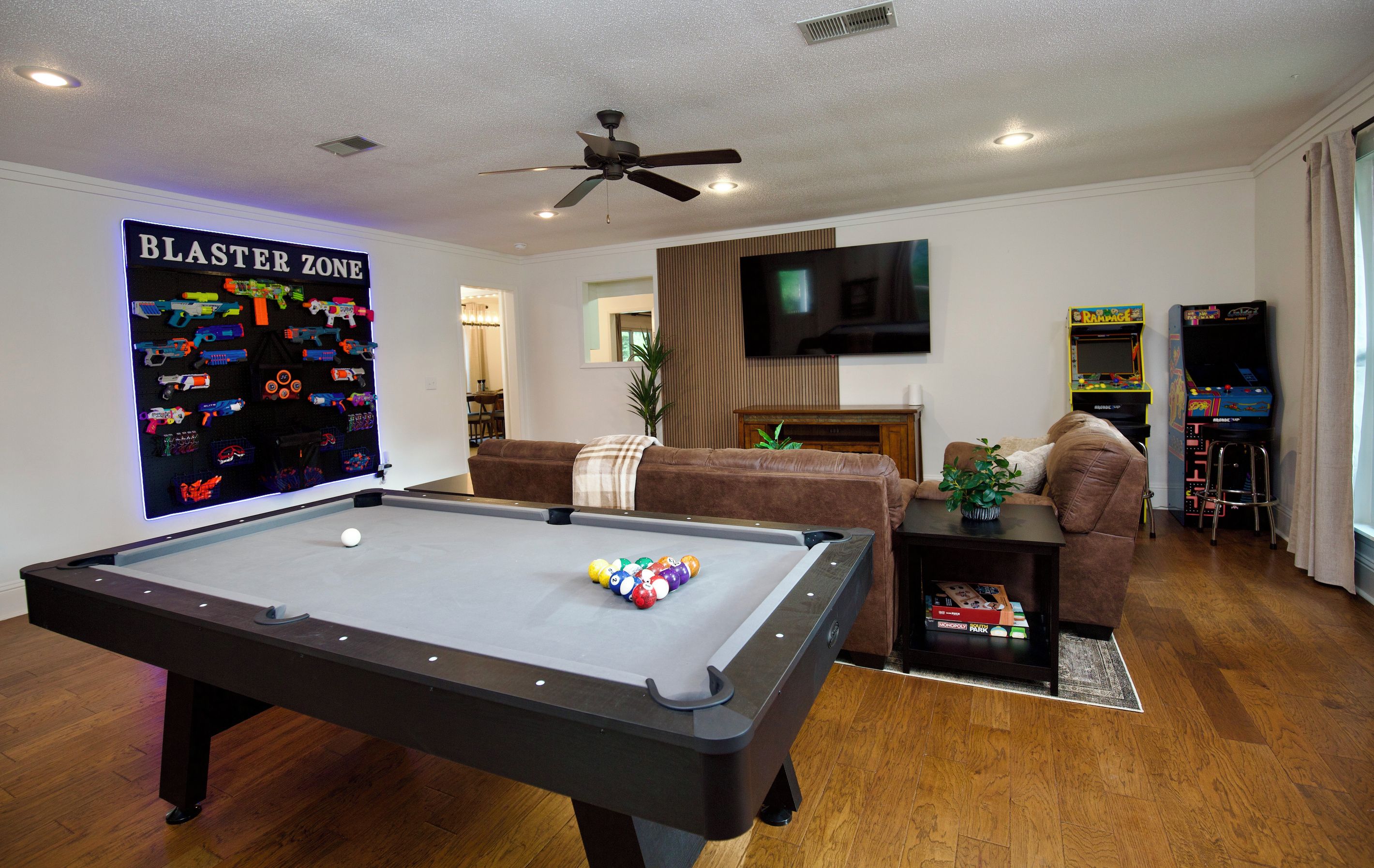 Una sala de estar con mesa de billar, televisi ón y juegos de arcade.
