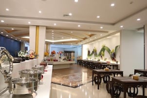Comedor de hotel con barra libre, varias mesas de comedor y una estación central de servicio.