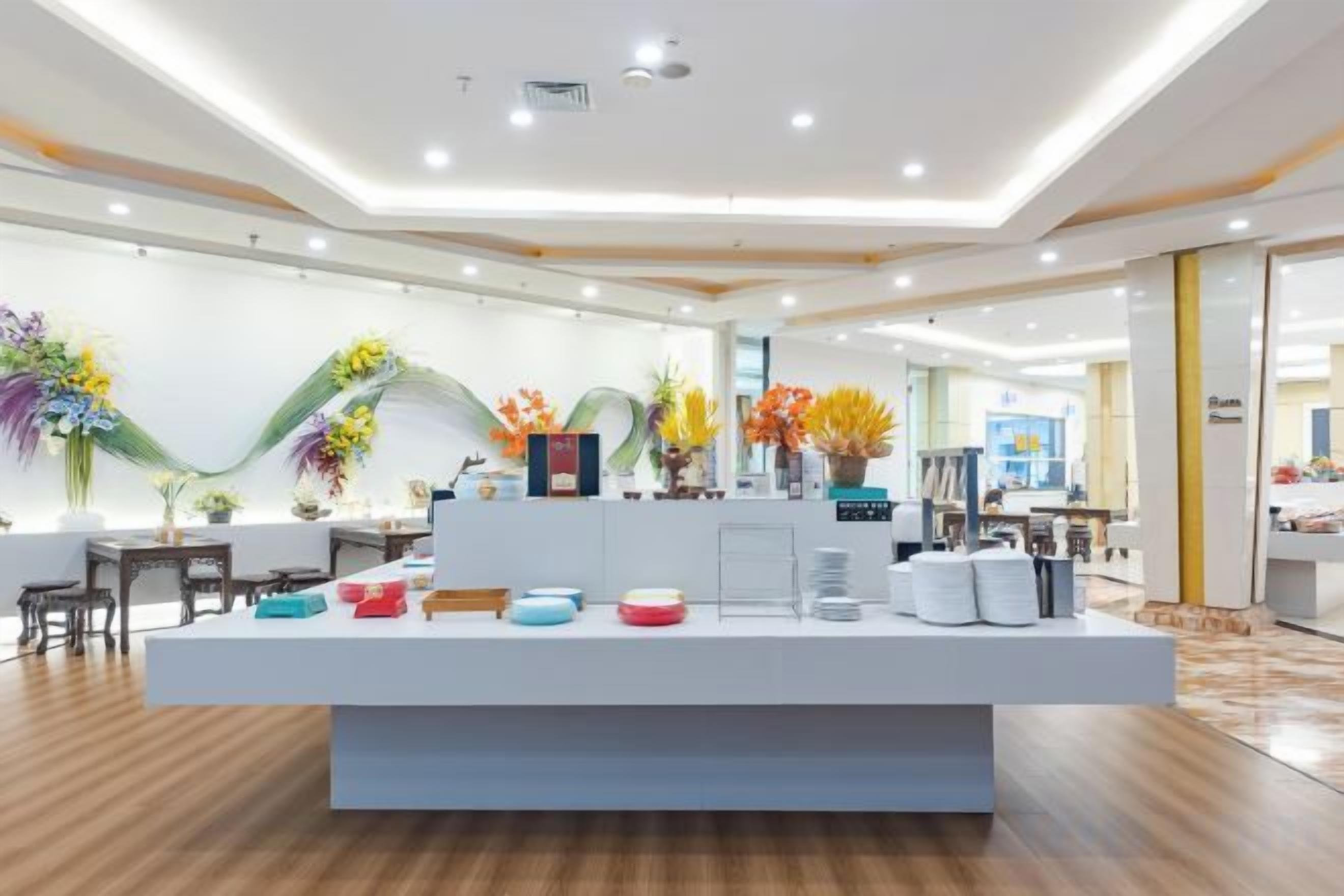 Un vestíbulo moderno de hotel con mostrador de recepción, plantas decorativas y un interior limpio y bien iluminado.