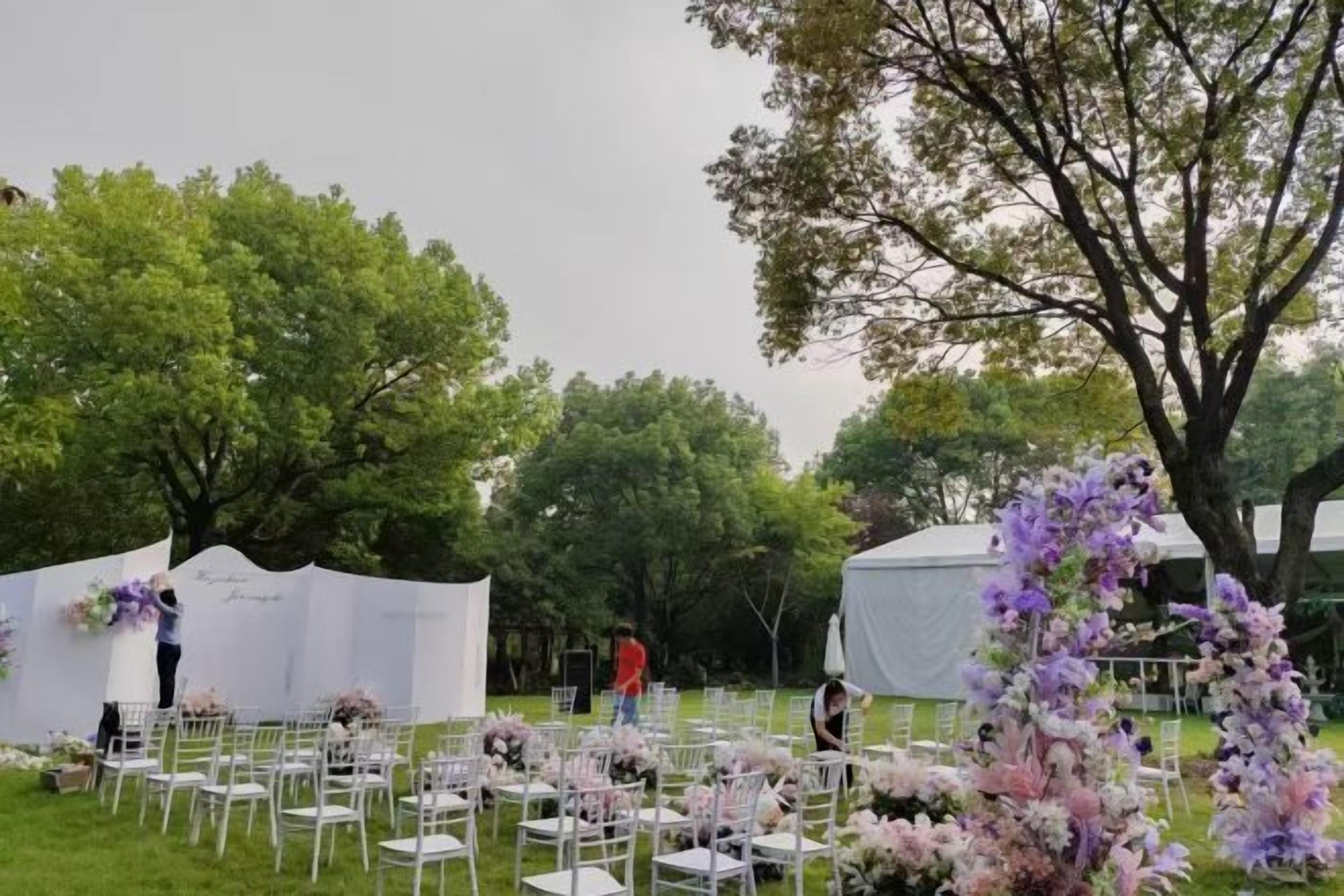 An outdoor event setup with white tents, tables, and chairs arranged for guests.