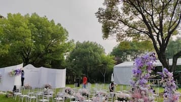 An outdoor event setup with white tents, tables, and chairs arranged for guests.