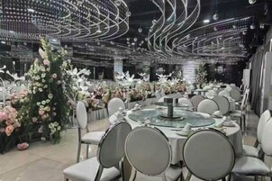 Un salón de banquetes con mesas redondas, sillas y arreglos florales.