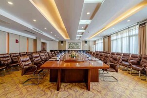 Una sala de conferencias con una larga mesa, sillas de cuero y suelo alfombrado.