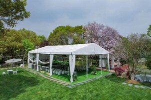 Una carpa blanca con un porche cubierto, rodeada de un césped cuidado y árboles.