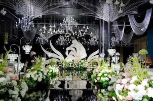 A luxurious interior with a reflective black floor, a central white sculpture, and elaborate chandeliers.