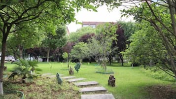 A garden with a stone pathway, various plants, and trees.