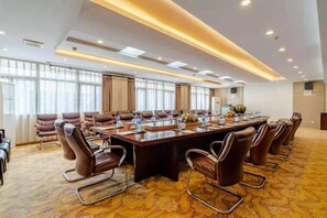 Una sala de conferencias con una mesa larga, varias sillas y piso alfombrado.