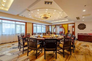 Un comedor amplio con una mesa redonda y sillas, ventanas grandes y un techo decorativo.