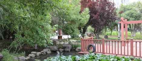 A tranquil garden with a pond, rocks, and a red fence.