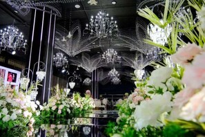 Une pièce décorée de lustres, agrémentée de compositions florales et dotée d’un sol réfléchissant.