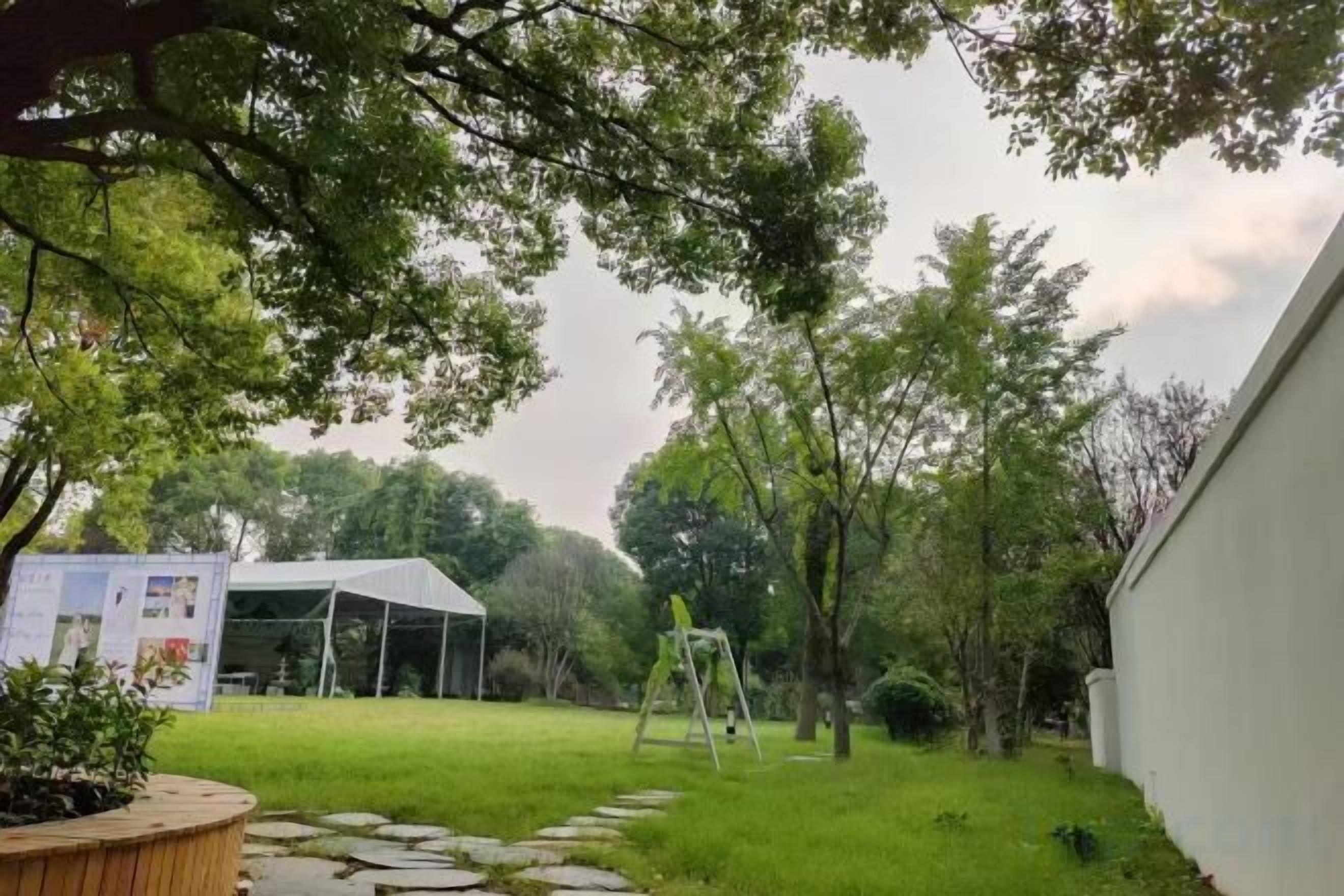 A backyard with a lawn, a white building, and a wooden deck.