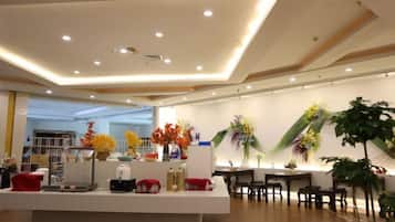 A hotel lobby with a reception desk, seating area, and decorative plants.