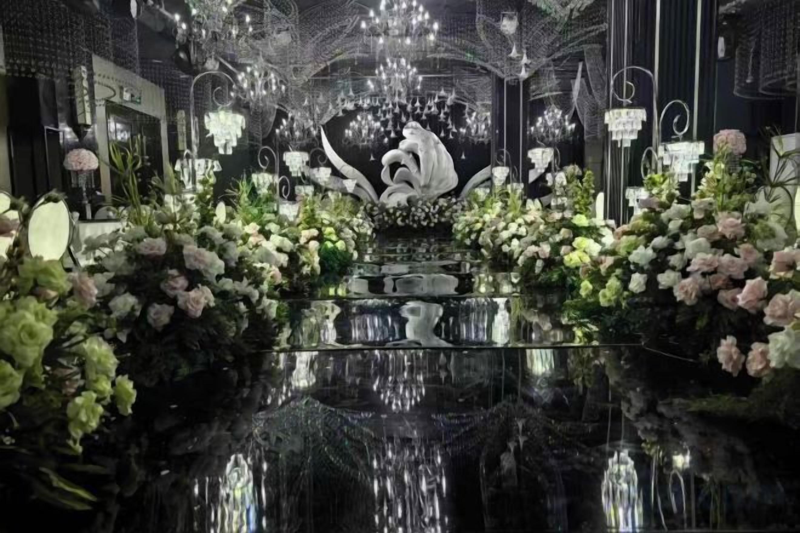 Un hall d’hôtel luxueux, doté d’un sol noir brillant, de lustres somptueux et de compositions florales.