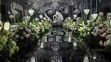 Un hall d’hôtel luxueux, doté d’un sol noir brillant, de lustres somptueux et de compositions florales.