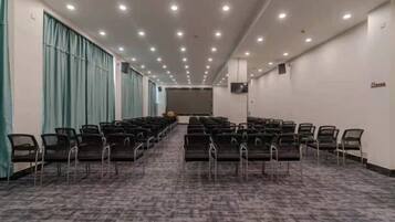 A conference room with rows of chairs, a carpeted floor, and a projector screen.