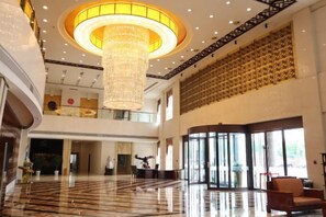 A spacious lobby with a large chandelier, a reception desk, and a seating area.