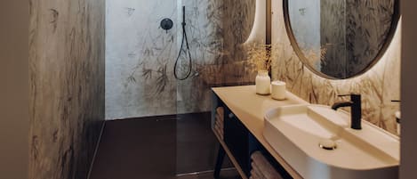 A modern bathroom with a large mirror, two sinks, and a walk-in shower.