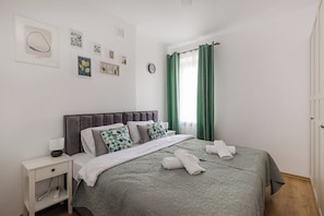 A bedroom with a bed, nightstand, and wall art. - Spacious apartment on Białobrzeska Street for 4 guests, in a great location. (Warszawa)