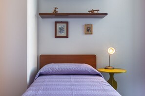 A bed with a headboard, a bedside table with a lamp, and two framed pictures on the wall. - GuestHost - MIRA-MARE Apartment with Parking (Quartu Sant'Elena)
