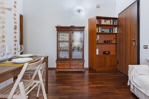 Ein Zimmer mit einem Holztisch, gedeckt für zwei Personen, einem Schrank mit Glastüren und einem Bücherregal.