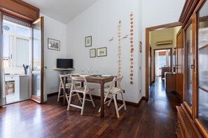 A dining area with a wooden table and chairs, a television, and wall decorations. - GuestHost - MIRA-MARE Apartment with Parking (Quartu Sant'Elena)