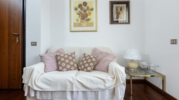 A room with a sofa, a lamp, and two framed artworks on the wall. - GuestHost - MIRA-MARE Apartment with Parking (Quartu Sant'Elena)