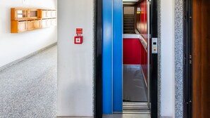 An elevator with a blue interior, a red carpet, and a fire alarm box on the wall. - GuestHost - MIRA-MARE Apartment with Parking (Quartu Sant'Elena)