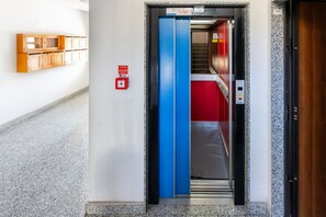 An elevator with a blue interior, a red carpet, and a fire alarm box on the wall. - GuestHost - MIRA-MARE Apartment with Parking (Quartu Sant'Elena)