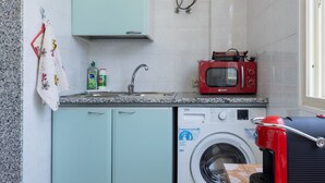 A compact kitchen with a washing machine, a microwave, and a sink. - GuestHost - MIRA-MARE Apartment with Parking (Quartu Sant'Elena)