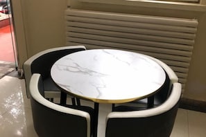 A round table with a marble top, surrounded by black chairs.