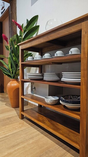 A wooden shelf unit with white and patterned bowls, plates, and cups. - Casa Sossego in Arraial d'Ajuda (Arraial d'Ajuda)