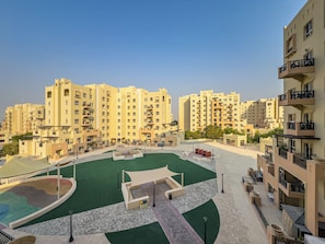 A residential complex with multiple high-rise buildings, a central courtyard with green artificial turf, and outdoor seating areas. - Studio Retreat In Reemram Pool & Gym (Dubai)