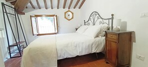 Ein Schlafzimmer mit einem Bett, einem Nachttisch aus Holz, einem Fenster und einer Tür.